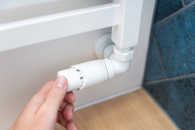 Modern beyaz radyatör, el ele tutuşan termostat, kapat