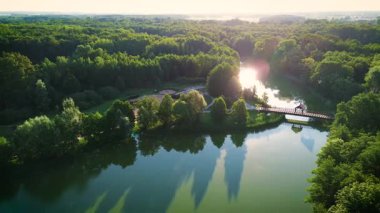 Gün doğumunda sakin bir park, huzurlu bir gölet ve yemyeşil bir yer.