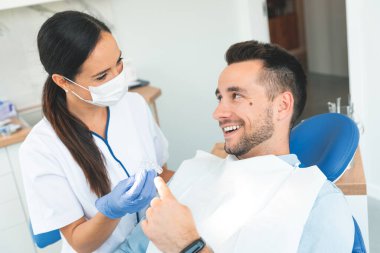 Diş hekimi, dişçide bir hastanın dişlerini muayene ediyor. Ortodonti aygıtı