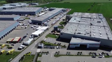 Wroclaw, Polonya - 26 Nisan 2025: Birçok kamyon ve araba park edilmiş büyük sanayi bölgesinin havadan görünüşü. Gökyüzü mavi ve çimenler yeşil