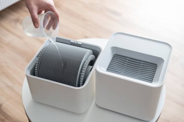 Modern hava nemlendirici oturma odasında. Rahat yaşam koşulları. Filtre değiştiren adam