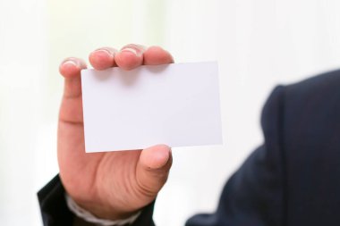 Siyah takım elbiseli iş adamının elinde beyaz bir isim kartı var.
