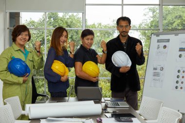 Mühendislerin dört sekreteri ve şefi güvenlik kaskı ve yumruklarıyla toplantı odasında duruyorlar.