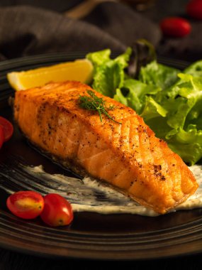 Izgara ya da kızarmış somon bifteği ve yeşil salata, limon, domates, sos, meze. Pişmiş balıklı sağlıklı geleneksel deniz ürünleri.