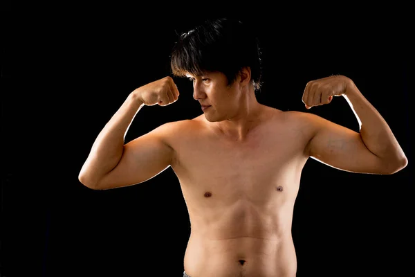 若いです自信のあるアジア人男性無気力なポーズ黒の背景に二本の腕の筋肉 — ストック写真