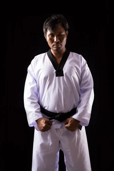ブラックベルト Taekwondoアジアの男性アスリート男性は黒を背景に伝統的な格闘ポーズJunbiを示しています テコンドーのダイナミックな世界を探索してください スポーツ愛好家やコンセプチュアル アートに最適 — ストック写真