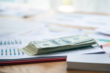 Amerikan doları banknotuyla renkli bir satış tablosu sunmak, para birimi ve iş performansının kesişimini sembolize etmek, finansal büyümeyi vurgulamak