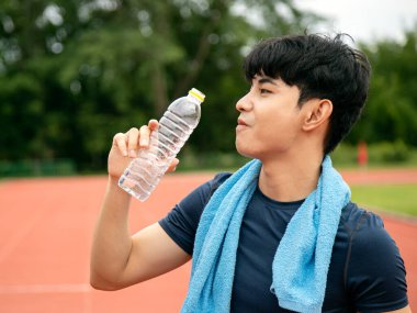 Yakın plan çekimde bir sporcunun ferahlatıcı bir arayla susuzluğa olan bağlılığı, fotokopi alanındaki performansı için susuz kalmamanın önemini vurguluyor.