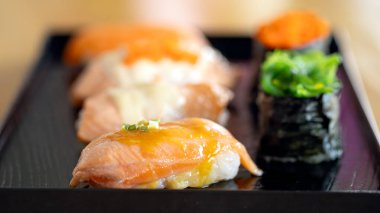 An enticing array of sushi, prominently featuring salmon and tobiko, artfully placed on a chic black serving plate clipart