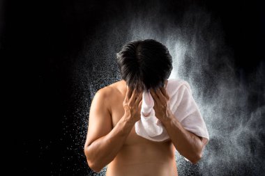 With a background of water droplets, an Asian young man uses a white towel to dry his face after a workout, highlighting the refreshing conclusion of his physical activity clipart