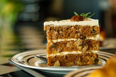Close-up of one slice of carrot cake with cream cheese frosting and pecan garnish, served on plate clipart