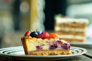 Taze çilek, yaban mersini ve biberiyeyle kaplı bir dilim karışık çilekli cheesecake.