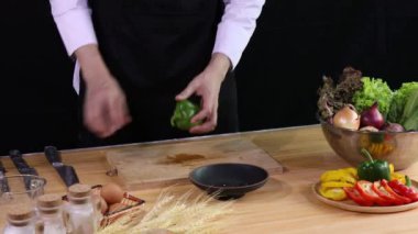 Genç aşçı, mutfak tezgahına taze sebze, yumurta ve baharatla dilimlenmiş yeşil dolmalık biberi koyuyor.