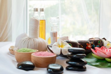 Bitkisel kompres, gerekli yağlar, mumlar, taşlar ve aromatik tuzlar içeren huzurlu ve rahatlatıcı bir spa düzeneği.