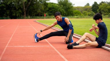 İki genç adam serinliyor ve yoğun idmandan sonra koşuya devam ediyor. Açık havada esneklik ve iyileşme.
