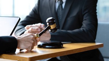 Hukuki bir tartışma sırasında elinde tokmak tutan bir yargıç ya da avukatın yakın plan çekimi adalet, karar verme ve mahkeme otoritesini sembolize eder.