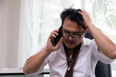 Hüsrana uğramış bir ofis çalışanı telefonda konuşurken eli başındaydı. Stresli bir iş ortamında bunalmış ve endişeliydi.