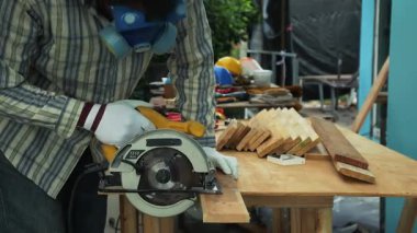 Marangoz, emniyet teçhizatı ve eldiven giyerken tahta levhayı ataçla işaretliyor.