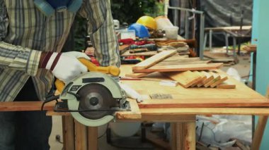 Marangoz, ahşap tahta üzerinde koruyucu maske çizgisi ile açık hava atölyesinde kare araç kullanıyor.