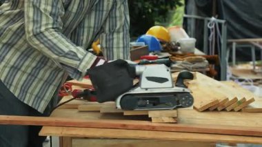 İşçi zımpara tahtası, elektrikli kemer zımpara makinesi açık hava marangozluğu atölyesinde tezgahta.