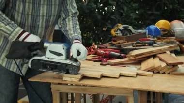 Marangoz ahşap kalasları elektrikli zımpara ile zımparalıyor.