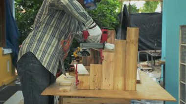 Marangoz, tahta kalasları dikey kereste montajına yerleştirmek için pnömatik çivi tabancası kullanıyor.