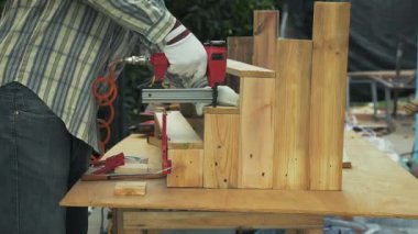 Eldivenli işçiler, marangozluk sırasında tahta levhaları basamaklı yapıya tutturmak için çivi tabancası kullanıyorlar.