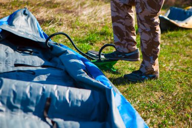 Adam pompayla lastik bir tekne şişiriyor.