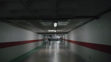 Yeraltı otoparkının boş garaj yolunun kasvetli manzarası. Donuk uzayda, beton duvarları ve zemini olan titrek bir ışık.