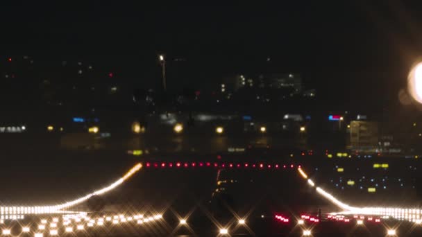 私人喷气式飞机夜间降落在机场的跑道上 在装有照明窗的住宅楼的背景下 被泊车灯明亮地照亮着 — 图库视频影像
