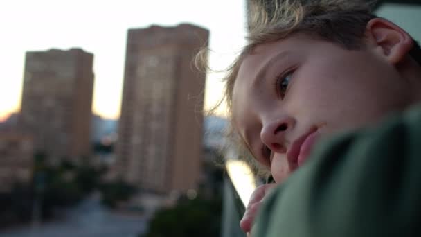 拍下了一个眼睛里充满悲伤的青少年的特写 男孩靠在阳台扶手上 看着城市的景象 — 图库视频影像