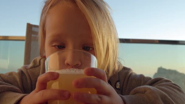 ジュースのレモネードを飲んで ガラスを見ている少女のクローズアップショット バルコニーで喉の渇き面白い子供 — ストック動画
