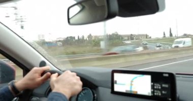 Şehrin banliyölerinde gezen ve güzergahı belirlemek için GPS cihazını kullanan bir araba sürücüsü. Yağmur çiselerken çalışan cam silecekleri