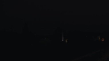 Kırsal yolda ilerleyen iki arabanın gece görüşü ve farlarla aydınlatma, virajda kaybolan araçlar ve karanlık geliyor.