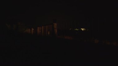Gece görüş alanı çitlerle kaplı ve hareket halindeki araba farlarla aydınlatıyor.