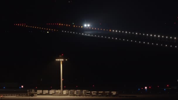 明るく照らされた空港滑走路上の夜の飛行機の土地 ヘッドライトがついている2番目の旅客機 離陸準備のための課税 — ストック動画