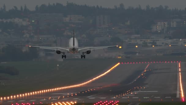 スローモーション 夕暮れ時に延長された着陸装置を備えた空港滑走路における旅客機の着陸 — ストック動画