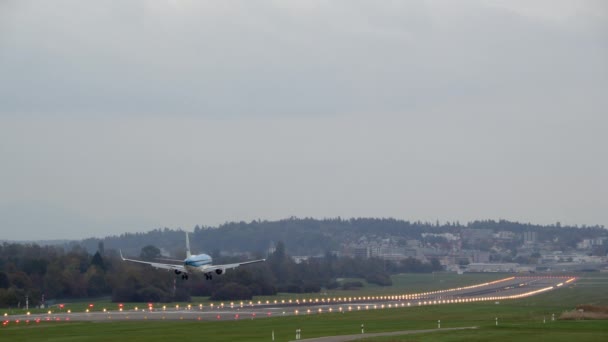 明るく照らされた滑走路上の空港に着陸した青い輸送機の旅客機 — ストック動画