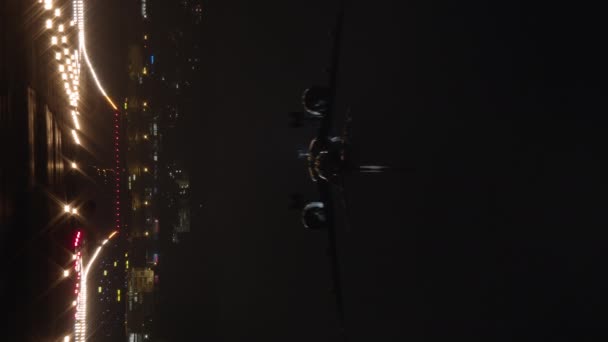 垂直ビデオ 黒の空に対して明るい滑走路に夜に着陸 上の駐車灯を備えた旅客用飛行機 — ストック動画