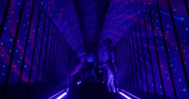 Children visiting amusement park. Two kids walking through the dark tunnel with spinning starry sky imitation