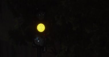 Yanıp sönen sarı ışıklar takip eden yeşil ışıklar, karanlık yağmurlu gecelerde manzara. Trafik yönetmeliği