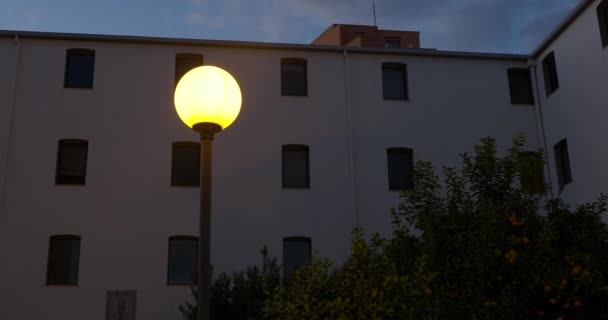 Statisk Kvällsbild Husvägg Brinnande Lampa Blå Aftonhimmel Buskage — Stockvideo