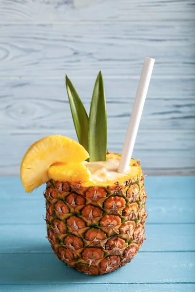 Dikey fotoğraf - Ananas dilimli Pina colada kokteyli, saman, mavi tahtada duran iki yeşil yaprak