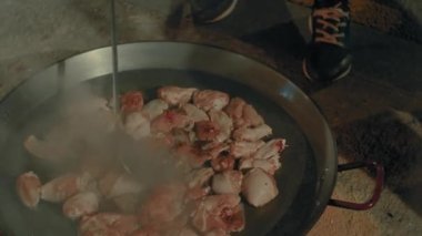Şef büyük bir tavada tavuk pişiriyor ve Valencia 'daki Fallas festivali sırasında test için bir parça çıkarıyor.