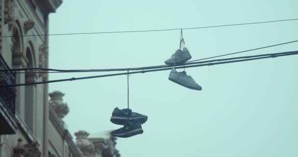 Ένα Ζευγάρι Αθλητικά Παπούτσια Κρέμονται Από Ηλεκτρικά Καλώδια Ανάμεσα Δύο — Αρχείο Βίντεο