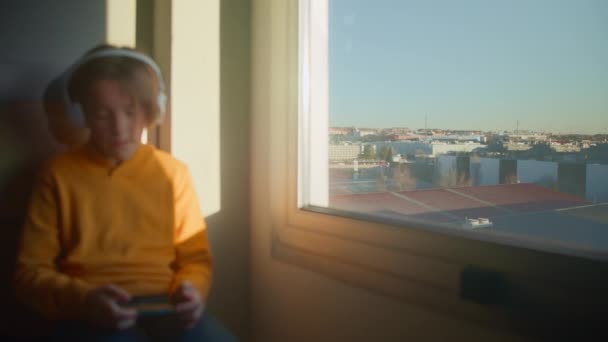 Year Old Teenager Sits Window Overlooking City Wearing White Headphones — Stock Video