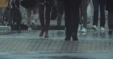 İnsanlar yağmurdan ıslanmış bir şekilde yaya geçidinde hızla karşıya geçiyorlar.