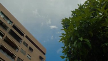Pencerelerinde kapalı panjurlar ve camlı balkonları olan modern bir binanın alçak açılı görüntüsü.