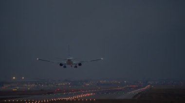 Gece inen uçaklar, aydınlatılmış pist boyunca parlak yan ışıklar.