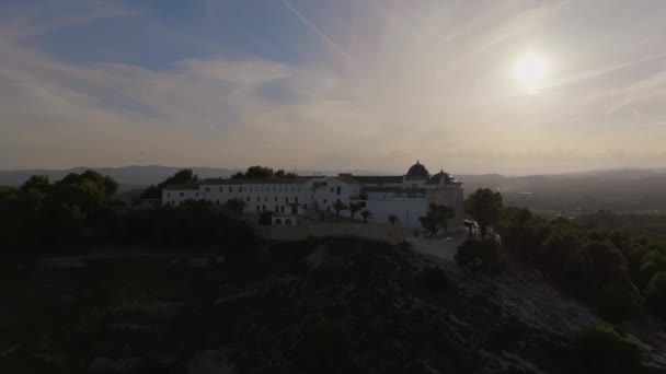 木々に囲まれた丘の上に空中白い修道院の建物が一人で立っています — ストック動画